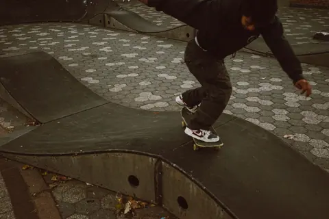 A skateboarder executes a trick on a curved ramp in an urban skatepark, showcasing skill and balance.