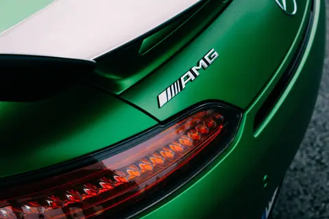 Detailed view of a luxury green sports car's tail light, highlighting sleek design and AMG branding.