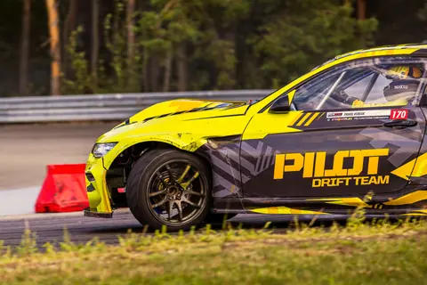 Yellow drift car speeding on racetrack during competition, showcasing precision driving.