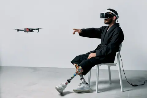Man with prosthetics using VR headset and drone indoors, embracing technology.