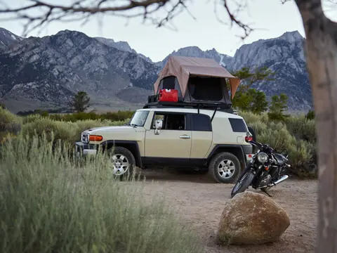 Off-road vehicle with rooftop tent in a scenic mountain landscape, perfect for an adventurous camping experience.