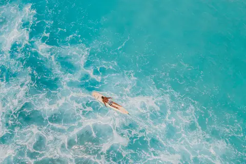 Aerial shot of a paddleboarder on the vibrant turquoise sea, capturing the essence of ocean relaxation.