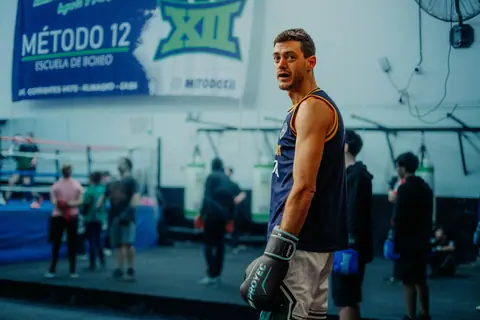 A focused boxing training session at a gym in Buenos Aires, Argentina, featuring a male boxer preparing in the ring.