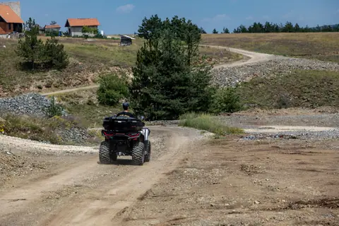 A person riding an ATV on a winding dirt path through the scenic landscapes of Zlatibor, Serbia.