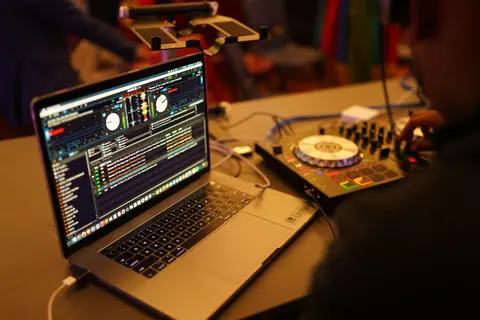 Close-up shot of a DJ setup featuring a laptop and audio mixer, ideal for music events.