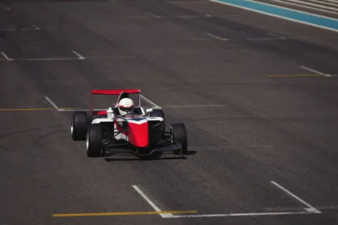 A formula race car speeds on the asphalt track at the iconic Abu Dhabi circuit.