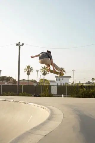 A skateboarder performs an airborne trick at a sunny skate park in Galveston, Texas.