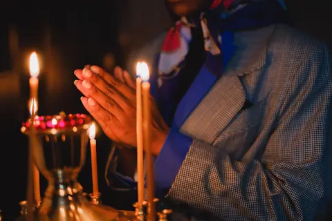 A person praying with candlelight, creating a warm and contemplative atmosphere.