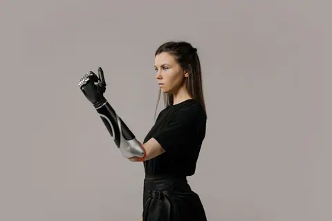 Portrait of a woman with a modern prosthetic arm in a studio setting.