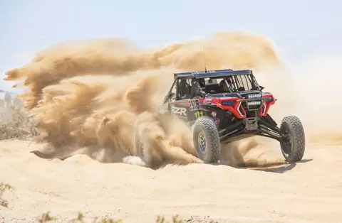 Exciting rally vehicle navigating the sandy terrain of Ensenada, Mexico, at high speed.