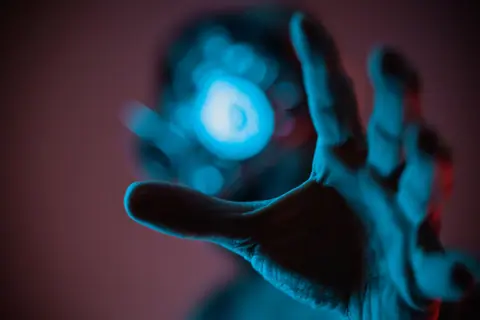 A mysterious hand reaching out towards a blue ethereal light, evoking a sense of wonder.