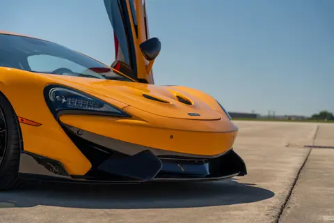 Striking orange McLaren sports car with doors open, captured on a sunny day in Illinois.