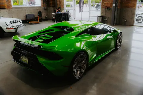 Vibrant green sports car displayed in an indoor showroom with sleek design and modern finish.