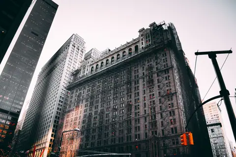 Low angle view of historic skyscrapers in New York City with dramatic lighting.