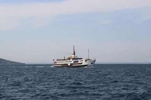 A passenger ferry cruises through the calm waters under a clear sky.