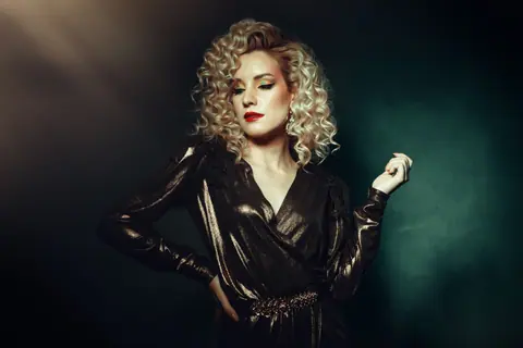 Elegant fashion portrait of a glamorous woman in a shining metallic dress posing confidently.