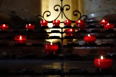 Red candles glowing in a church setting, providing a warm and serene atmosphere.