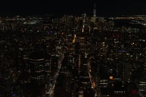Aerial view of New York City skyline at night with illuminated buildings.