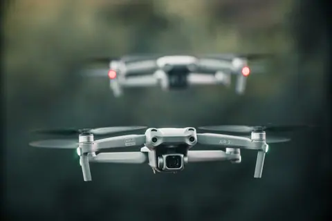 Close-up view of two drones in motion against a blurred background, outdoors.