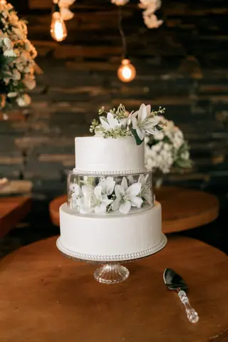Two-tier white wedding cake adorned with flowers, ideal for celebrations.