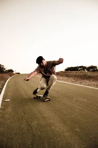 A skateboarder performing a trick on a deserted road at sunset, showcasing motion and balance.