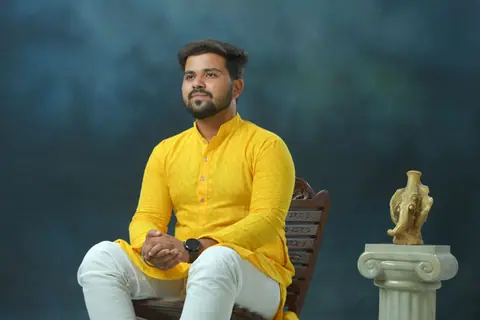 A man in a bright yellow kurta sits elegantly, showcasing traditional Indian attire.