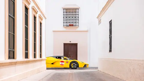 A yellow sports car parked between white buildings in a narrow urban alleyway, exuding luxury.