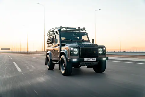 A Land Rover Defender cruises on a highway in Erbil during sunset, capturing speed and adventure.