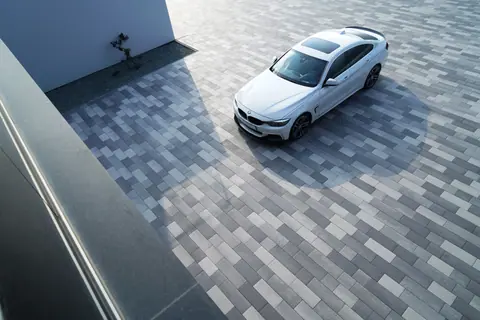 A white BMW 3 Series parked on contemporary geometric pavement, showcasing modern urban design.