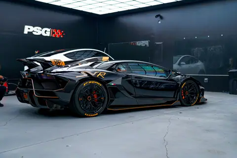 Black sports car with aerodynamic design in a sleek modern garage environment.