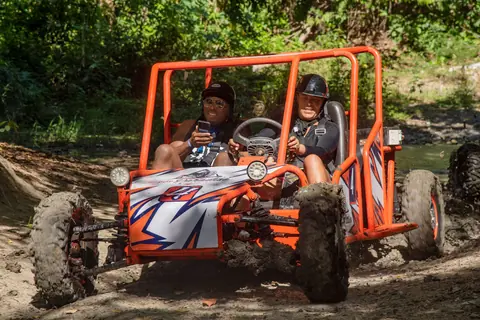 Two people drive an off-road buggy through mud on an adventure-filled day.