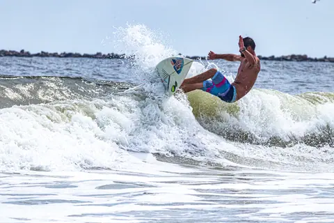 A male surfer riding a wave skillfully in the ocean, showcasing athleticism and balance.