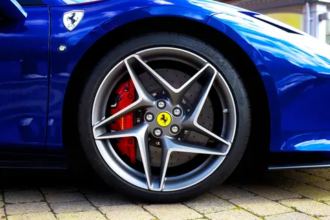Detailed shot of a blue sports car wheel and emblem in the UK.