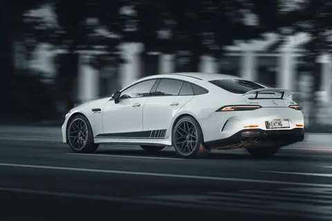 White luxury sports car speeding on a road, capturing motion and performance.