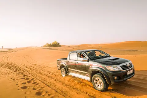 Explore the thrill of off-roading in a rugged pickup truck across expansive desert dunes under bright daylight.