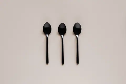 Top view of black teaspoon placed in line on beige background