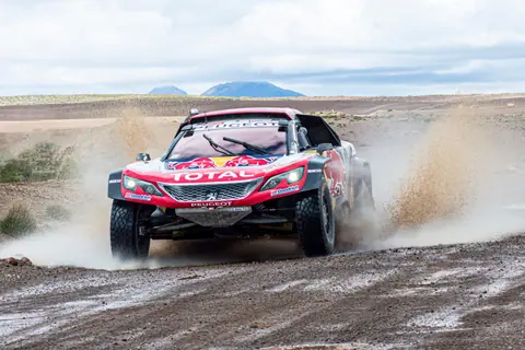 Peugeot rally car speeding through muddy terrain in Arequipa, Peru.