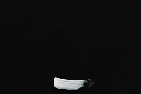 A minimalist artwork featuring a white paint stroke on a black canvas, emphasizing simplicity and contrast.