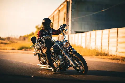 Biker rides a cruiser motorcycle on an open road during sunset, showcasing adventure and freedom.