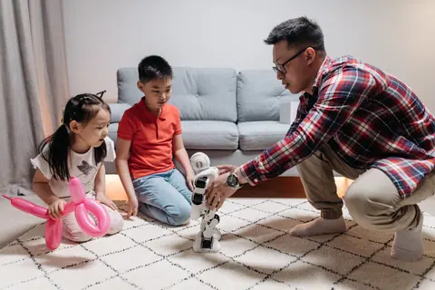 Father and children playing with a robot indoors, showcasing family and technology.