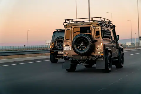 Stylish Land Rover vehicles cruising on an open highway during a stunning Erbil sunset in Iraq's Kurdistan Region.