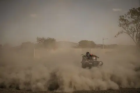 Dramatic off-road scene with a quad bike kicking up a trail of dust against a natural backdrop.