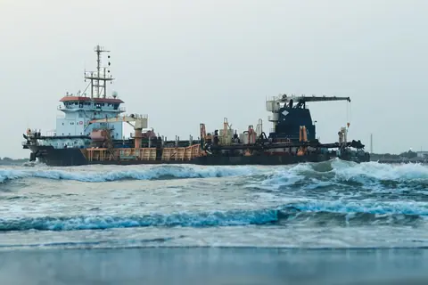 Large cargo ship navigating through ocean waves in Kochi, India.