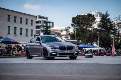 A modern BMW showcased at an outdoor car event with an urban backdrop.