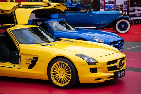 Close-up of vibrant yellow luxury car on display at an auto show, featuring sleek design and open doors.