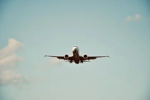 A commercial airplane in flight against a clear blue sky, representing air travel and transportation.