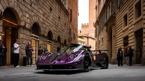Purple sports car parked in a historic Italian street with onlookers.