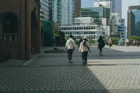 Pedestrians walk on a paved street surrounded by modern architecture in Seoul, South Korea.