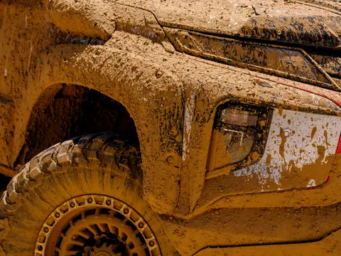 Close-up of a mud-covered offroad vehicle highlighting rugged details and terrain readiness.