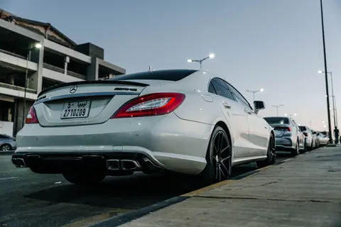 White Mercedes Benz CLS parked on an urban street in Tripoli, showcasing sleek design against a twilight backdrop.
